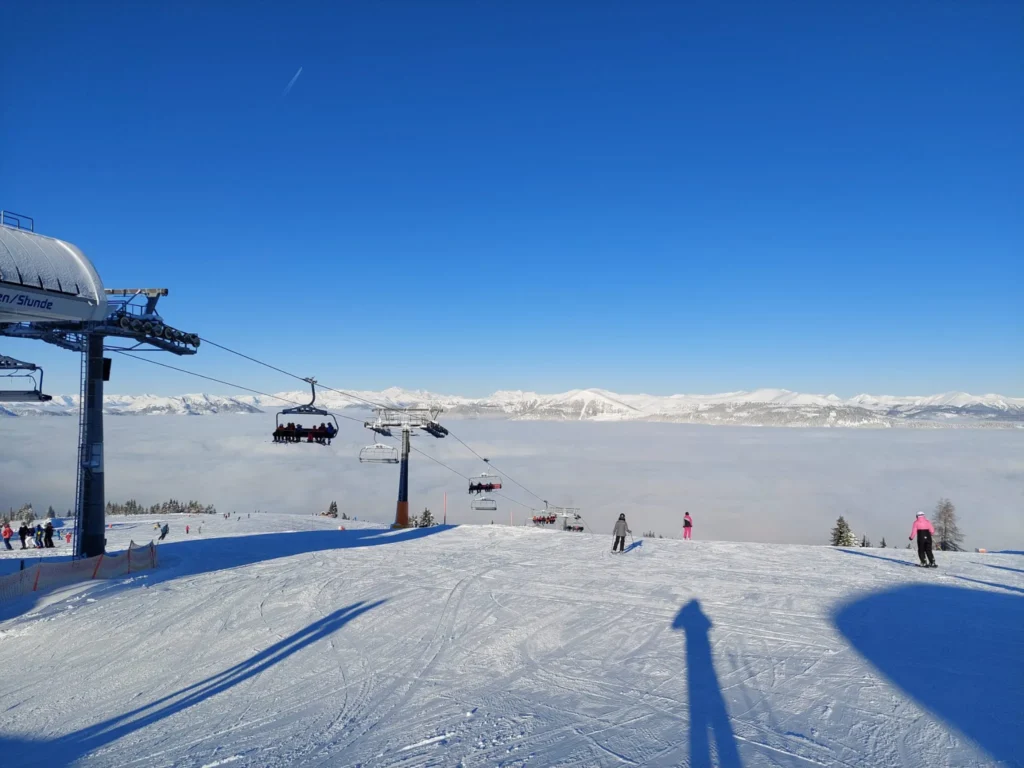 Sjedežnica iznad mora oblaka na Gerlitzenu, iza planinski lanac i vedro nebo