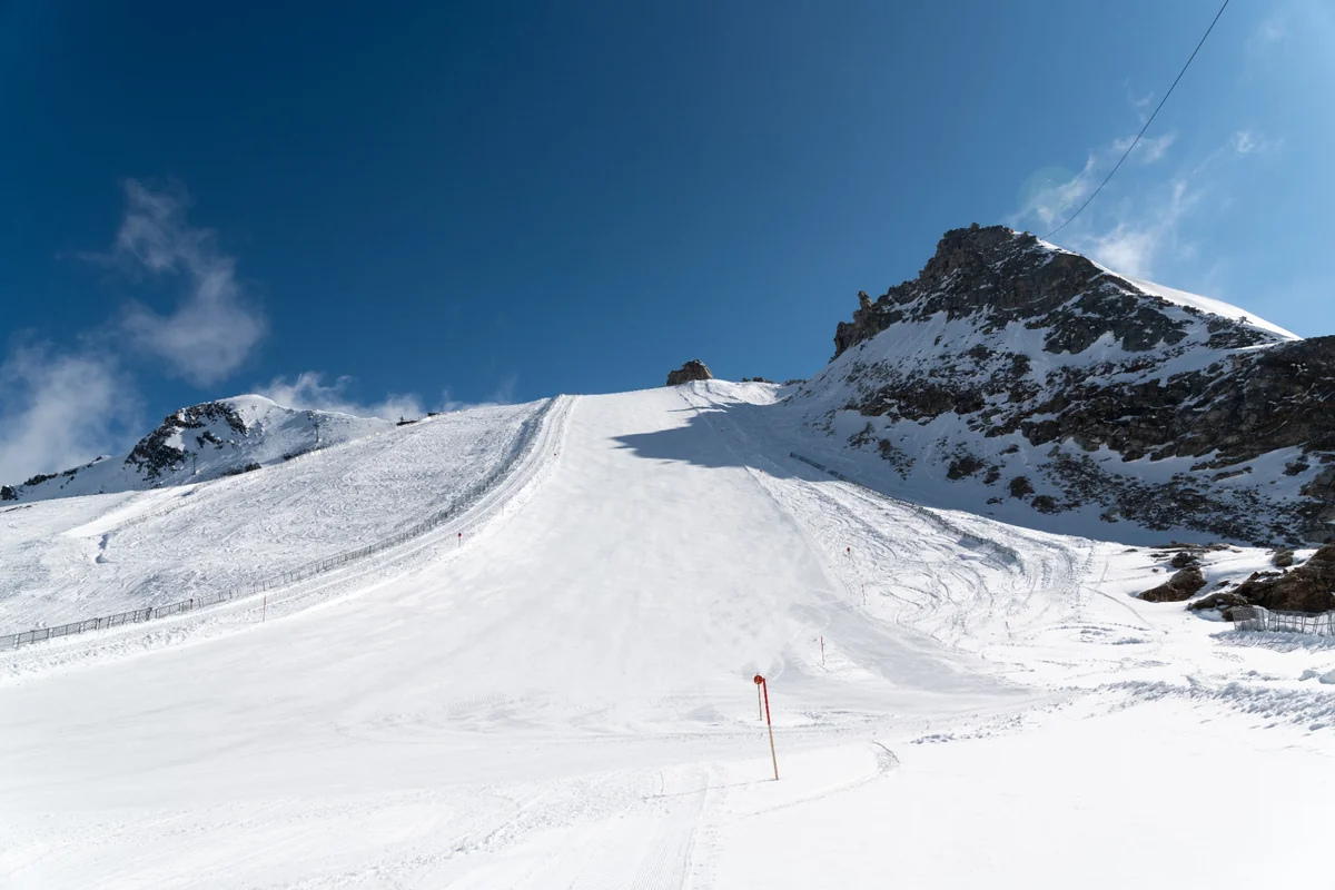 Uređena skijaška staza na ledenjaku Hintertux pod vedrim nebom, s kamenitim vrhom u pozadini